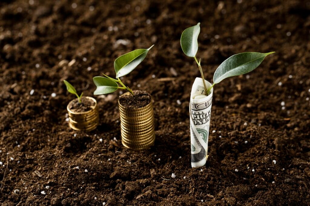 Will Land Prices Go Down in 2026 illustrated by growing plants emerging from soil and money, symbolizing land value appreciation