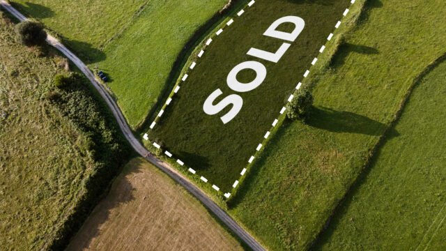 "A scenic aerial view of a sprawling one-acre land parcel in India, showing clear boundary markers and proximity to a developing highway, representing a strategic real estate investment."